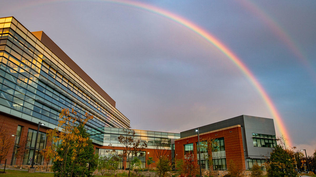 Peterson Hall, Home of the new College of Public Health at George Mason University viewed from the west vantage point on a cloudy evening with a rainbow appearing in the clouds above. 